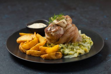 Kaynamış eklem, lahana ve fırında patates ile servis edilir. Ön manzara. Koyu mavi arka plan. Koyu mod. 