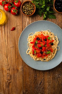 Domates ve zeytinli İtalyan spagetti alla Pultanesca. Et ve peynir olmadan servis edilir. Üst Manzara. Doğal ahşap zemin. 