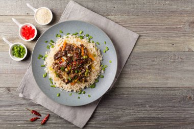 Geleneksel Kore Bulgogi yemeği. İnce dilimlenmiş, ızgara sığır eti, pirinç ve sebzelerle servis edilmiş. Üst Manzara. Doğal ahşap zemin.