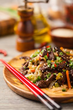 Geleneksel Kore Bulgogi yemeği. İnce dilimlenmiş, ızgara sığır eti, pirinç ve sebzelerle servis edilmiş. Ön manzara. Doğal ahşap zemin.