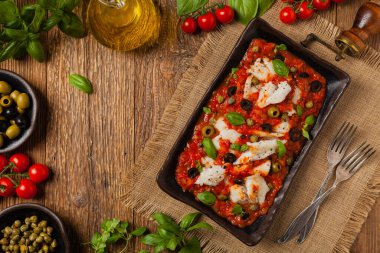 İtalyan usulü morina, domatesli zeytin ve kapari. Üst görünüm.