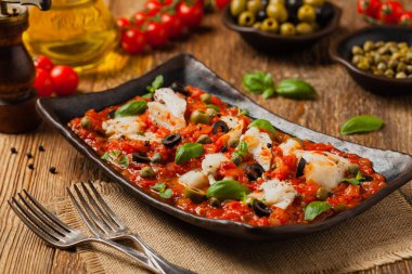 İtalyan usulü morina, domatesli zeytin ve kapari. Ön görünüm.