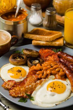 Tam İngiliz kahvaltısı, sosis, mantar, fasulye ve sahanda yumurta. Ön görünüm. 