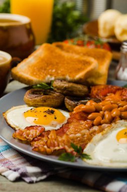 Tam İngiliz kahvaltısı, sosis, mantar, fasulye ve sahanda yumurta. Ön görünüm. 