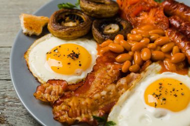 Tam İngiliz kahvaltısı, sosis, mantar, fasulye ve sahanda yumurta. Ön görünüm. 