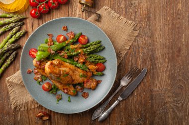 Kızarmış tavuk göğsü, kuşkonmazla servis edilen domates sosu, kurutulmuş domates. Üst görünüm.