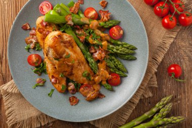 Kızarmış tavuk göğsü, kuşkonmazla servis edilen domates sosu, kurutulmuş domates. Üst görünüm.