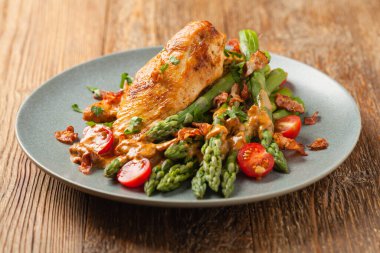 Kızarmış tavuk göğsü, kuşkonmazla servis edilen domates sosu, kurutulmuş domates. Ön görünüm.