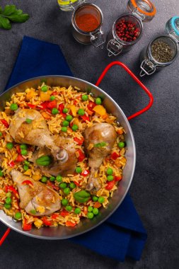 Arroz con pollo. Kemikli fırında tavuk, paprikalı pilav ve bezelye. Siyah arka plan. Siyah tabakta ya da İspanyol tavasında servis edilir.. 