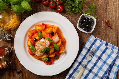 Geleneksel ispanyolca morina balığı. Domates sosunda haşlanmış patates, olivki ve fesleğen ile servis edilmiş. Üst görünüm. 