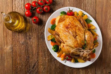 Kızarmış tavuk bütünü. Sebze ve fırında patatesle servis edilmiş. Düz yatıyordu. Üst görünüm. 