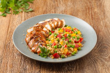 Teriyaki soslu ızgara tavuk göğsü. Kahverengi pirinç ve sebzelerle servis edilir. Ön görünüm. 
