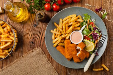 Patates kızartmalı balık ve gri tabakta salata. Üst görünüm.