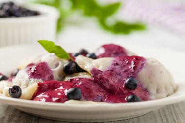 Krem şantili, şekerli ya da soslu taze yaban mersinli lezzetli hamur tatlısı. Parlak, ahşap arka plan. Ön görünüm.