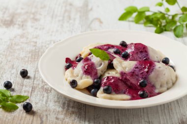 Krem şantili, şekerli ya da soslu taze yaban mersinli lezzetli hamur tatlısı. Parlak, ahşap arka plan. Ön görünüm.