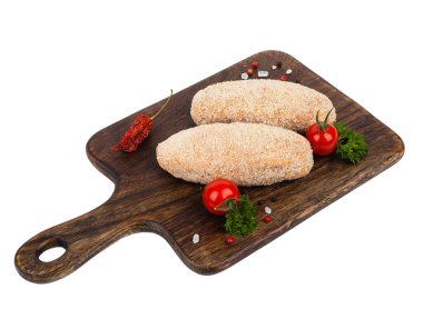 Çiğ kümes hayvanları tereyağlı pirzola. Kahverengi bir doğrama tahtasının üzerinde. Çörekte pişmiş. Paket atışı. Beyaz arkaplan.