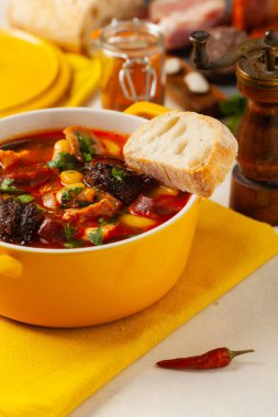 Geleneksel İspanyol gulaş çorbası. Fabada Asturiana. Kapaklı sarı kilden bir çömlekle servis edilmiş. Ön görünüm.