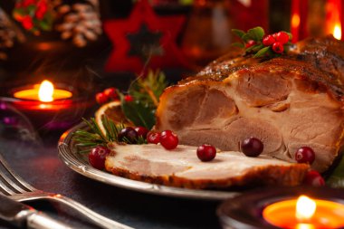 Noel tarzında kızarmış domuz boynu. Koyu lacivert arka plan. Noel aksesuarları. Arka planda mumlar ve fenerler..