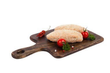 Çiğ kümes hayvanları tereyağlı pirzola. Kahverengi bir doğrama tahtasının üzerinde. Çörekte pişmiş. Paket atışı. Beyaz arkaplan.