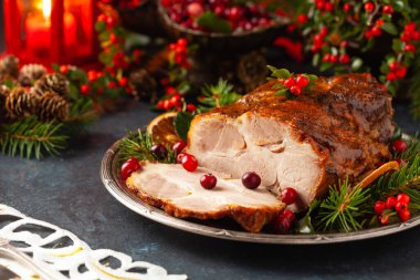 Noel tarzında kızarmış domuz boynu. Koyu lacivert arka plan. Noel aksesuarları. Arka planda mumlar ve fenerler..