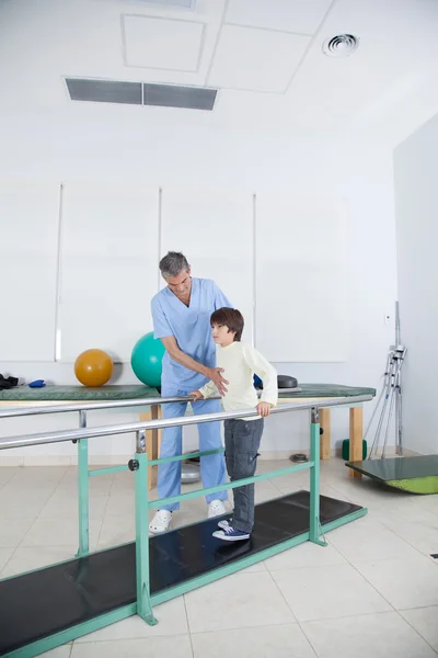 Terapeuta con chico en barras paralelas —  Fotos de Stock