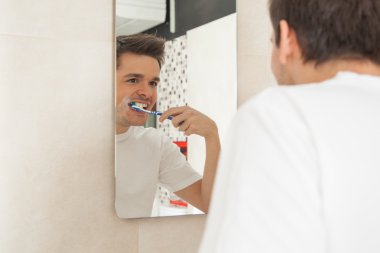 Adam dişlerini fırçalıyor. 