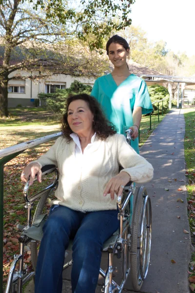 Nurse and a patient in a wheelchair in the park — Stock Photo, Image