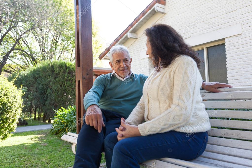 Elderly people talking on the park bench 