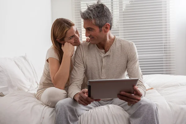 Pareja usando ipad en la cama — Foto de Stock