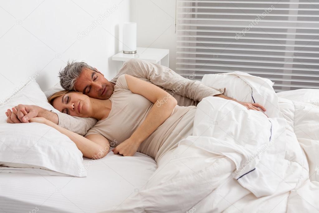 Embracing couple sleeping in bed