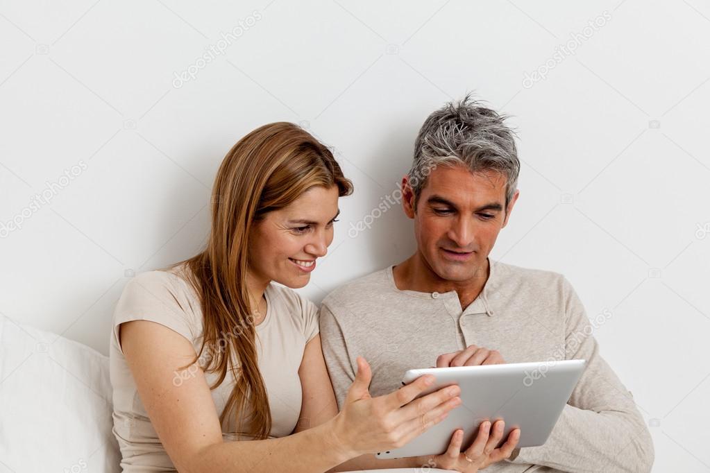 Couple using ipad in bed