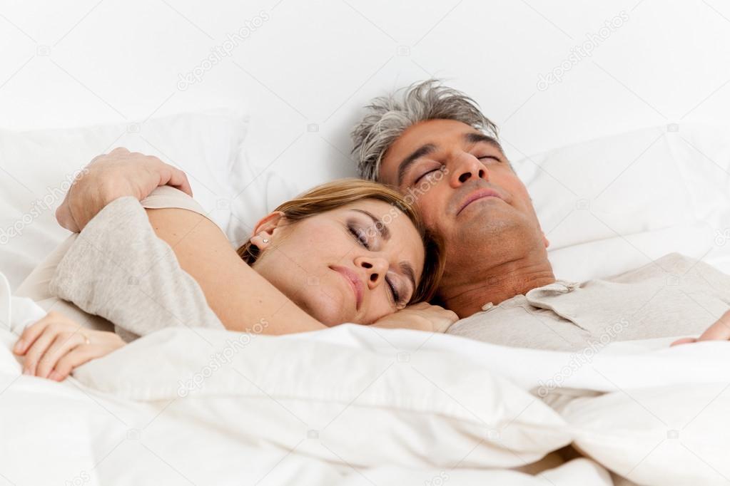Embracing couple sleeping in bed