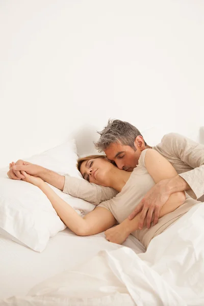 拥抱的夫妇睡在床上 — 图库照片