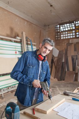 Masasında bir matkapla marangoz