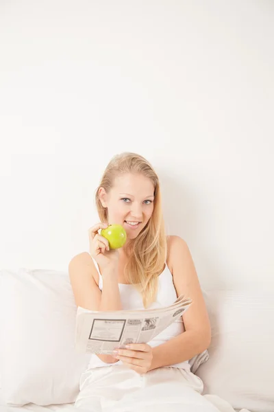 Mujer leyendo el periódico y comiendo una manzana —  Fotos de Stock