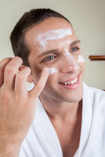 Chico feliz poniendo crema facial con tu dedo —  Fotos de Stock