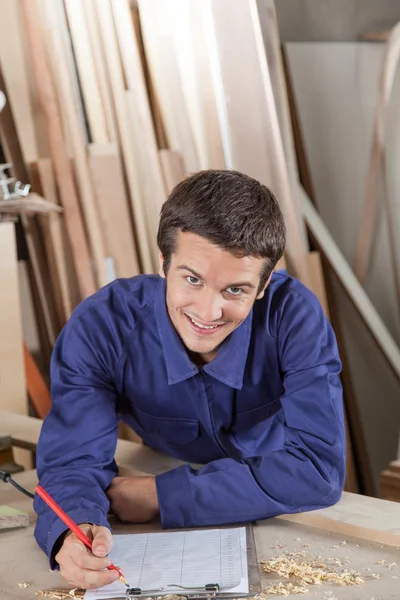 Happy man writing in his workshop — Stock Photo, Image