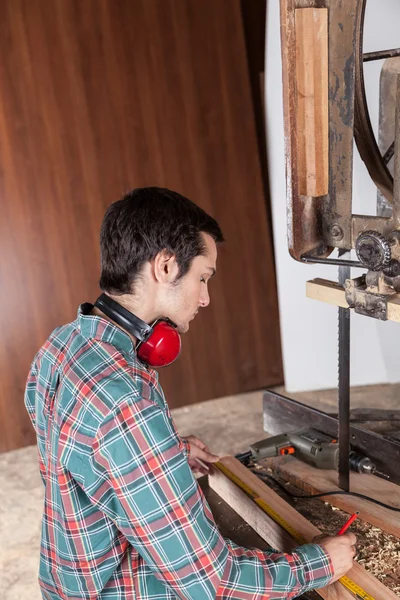 Hombre serio midiendo pieza de madera — Foto de Stock