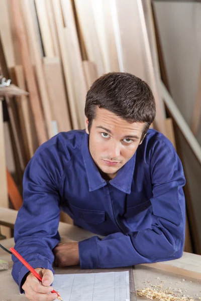 Carpenter writing in his workshop — Stock Photo, Image