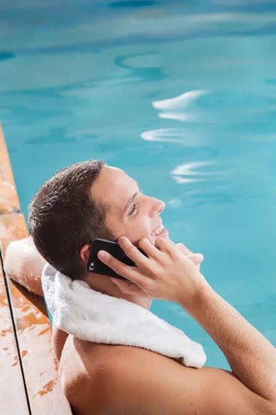 Мужчина разговаривает по мобильному телефону в бассейне — стоковое фото