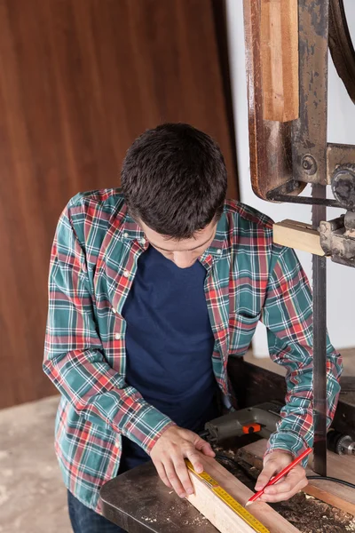 Guy meten een stuk hout — Stockfoto