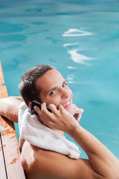 El hombre usa el celular en la piscina. — Foto de Stock