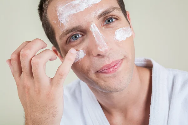 Hombre serio poniendo crema facial con el dedo —  Fotos de Stock