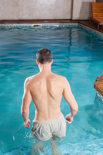 Junger schöner Mann tritt in den Pool ein — Stockfoto