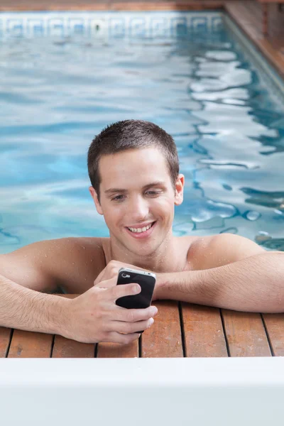 Férfi játék-a mozgatható telefon-ban egy medence — Stock Fotó