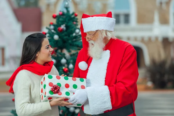 Der Weihnachtsmann schenkt einer jungen Frau — Stockfoto