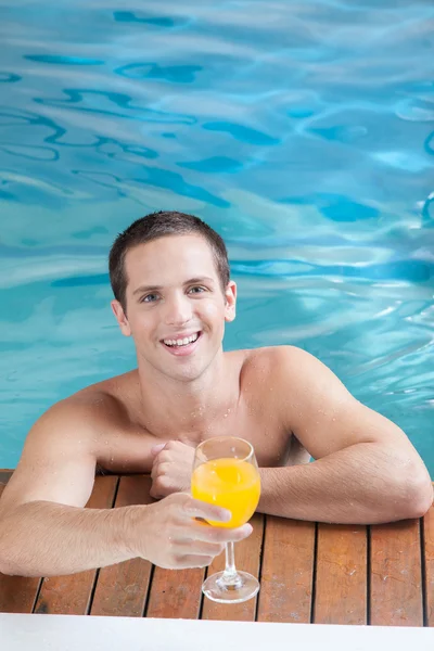 プールの中のジュースを飲む男性 — ストック写真