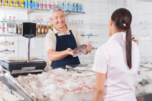 Mann schenkt einem Kunden einen weißen Lachs — Stockfoto