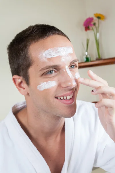 Happy man applying face cream — Stock Photo, Image