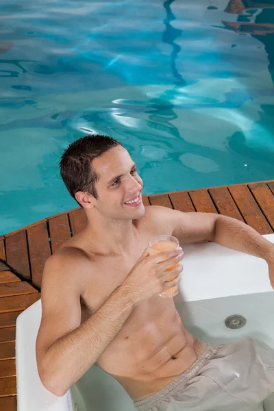 Homem dentro de um jacuzzi bebendo suco — Fotografia de Stock